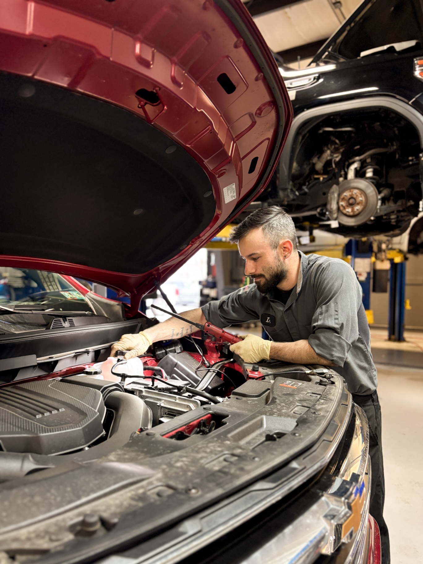 Patriot technician working on the engine bay of a red Chevrolet Equinox