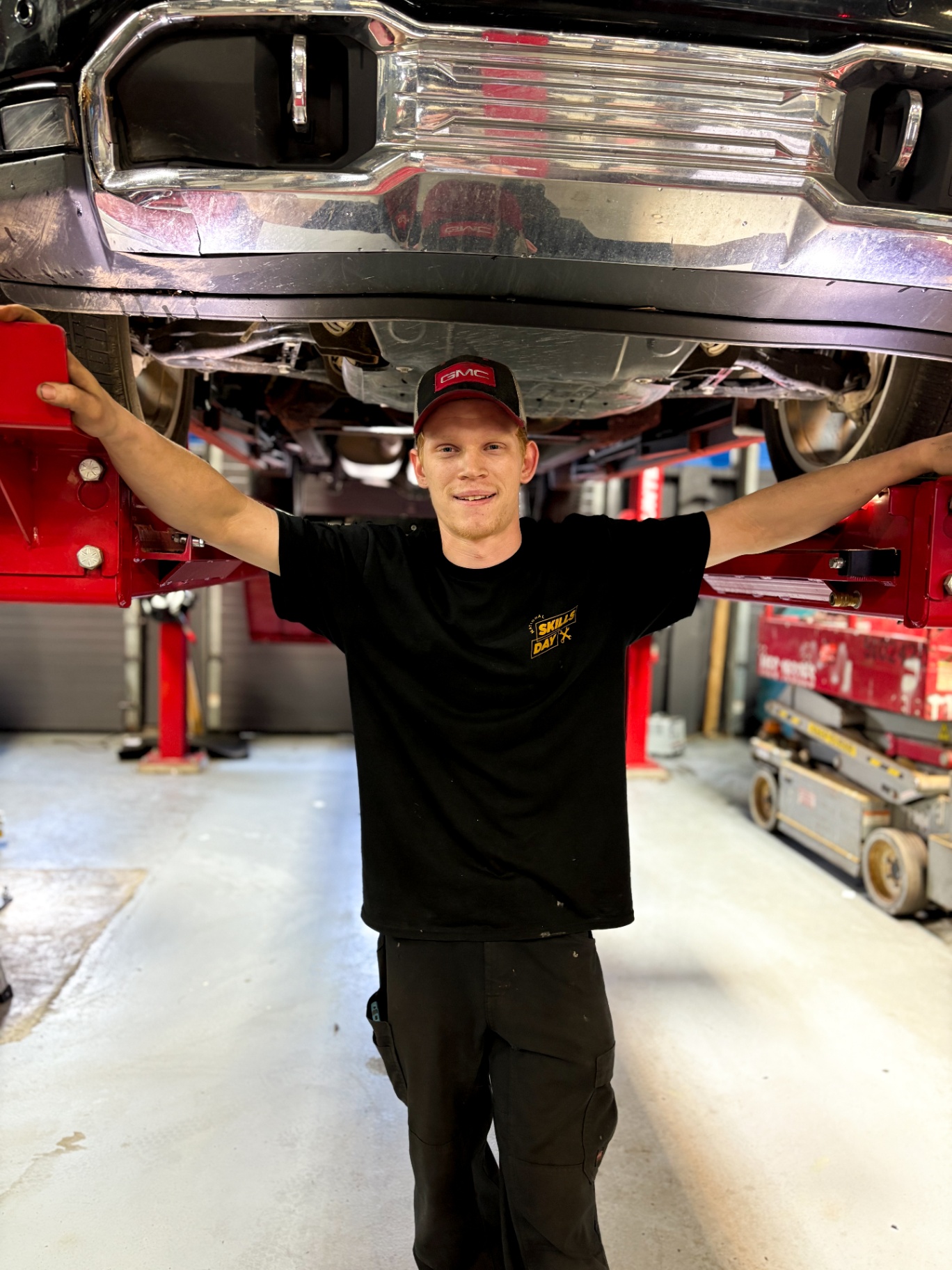 Patriot GMC technician standing under a lifted pickup during National Skills Day