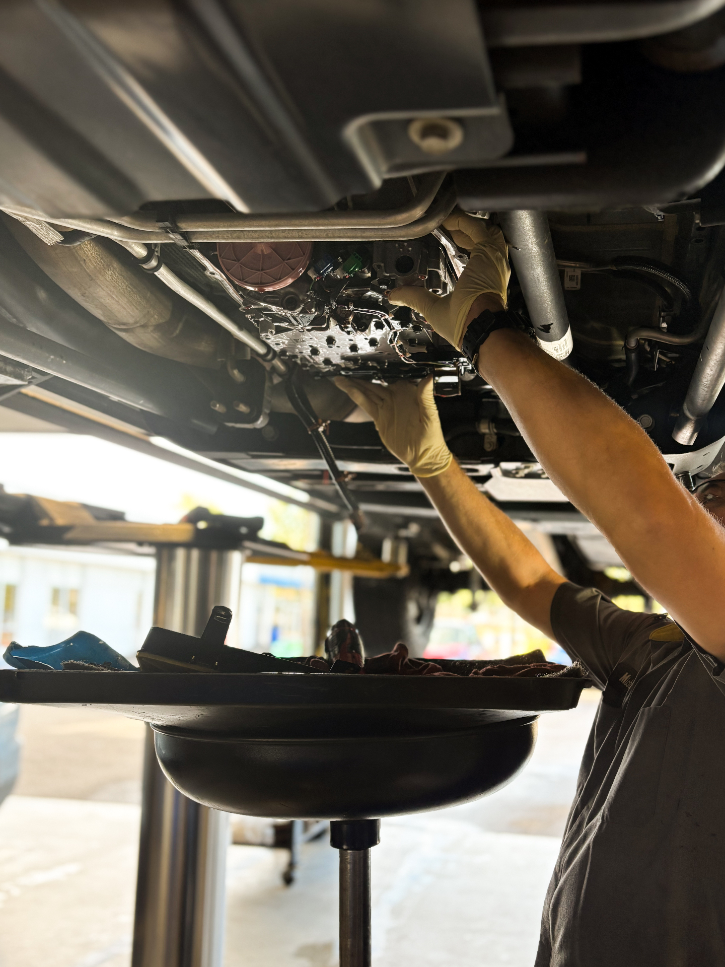 Patriot technician performing a transmission pan service on a lifted vehicle