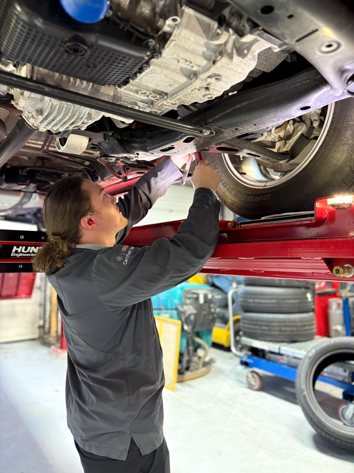 Young Patriot technician working underneath a vehicle on a lift